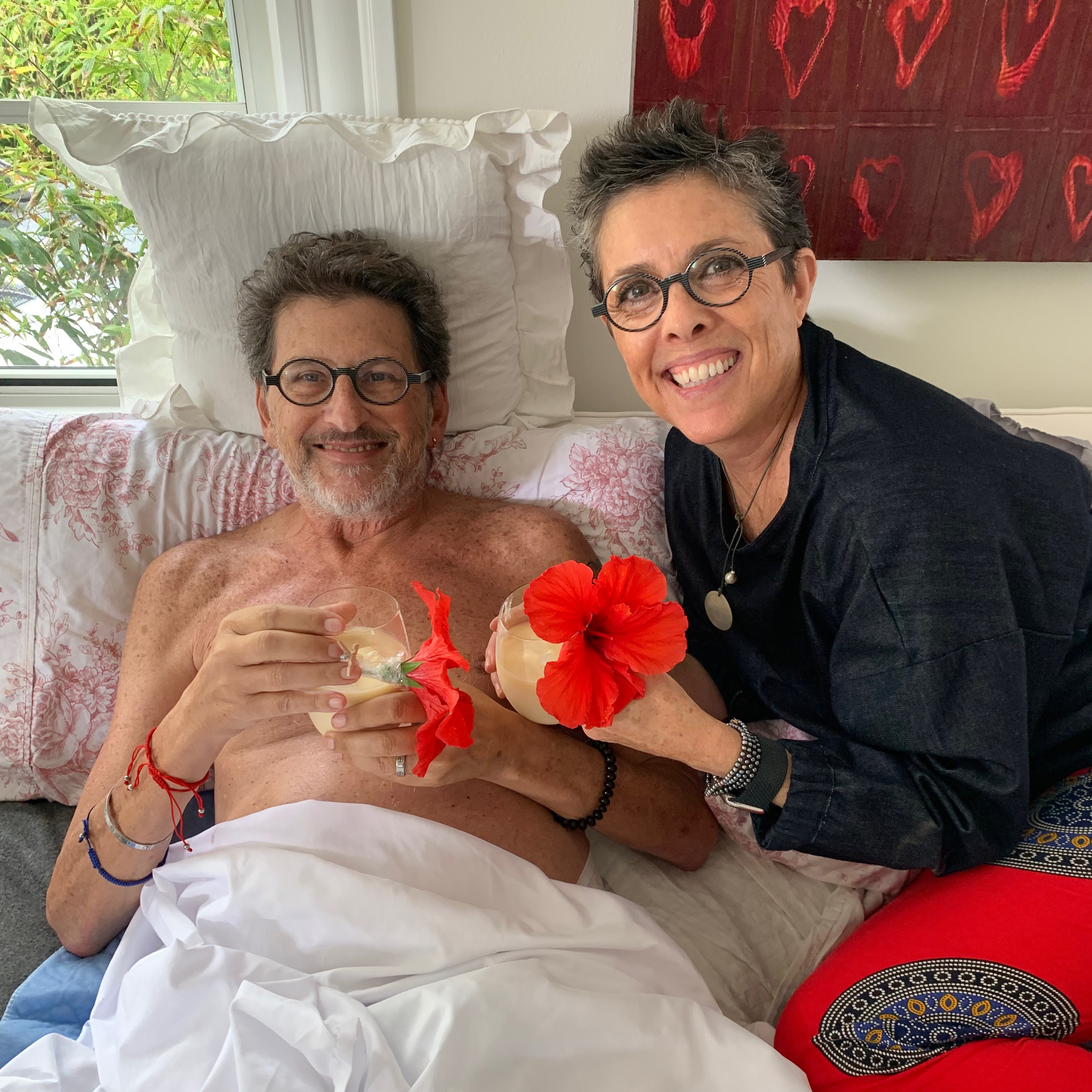 Alison Clay Duboff and her Husband Ken Duboff in a hospital bed with tropical drinks.
