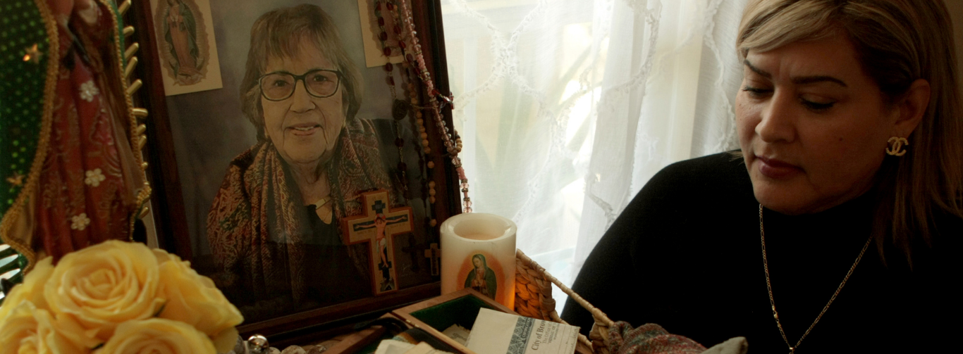 A woman seated next to a photo of her late mother