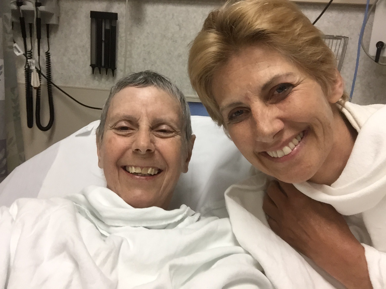 Mary Klein in a hospital bed with her wife Stella Dawson beside her