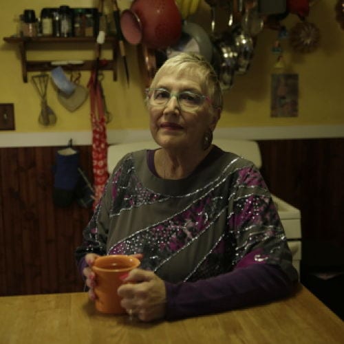 Deborah Stern seated at dining room table with coffee mug