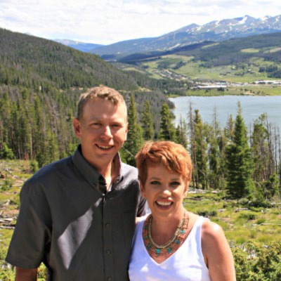 Jesse Ankerholz stands to the left of his wife Mimi in front of a picturesque mountain scene