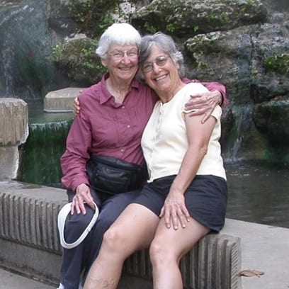 Myra and Beverly Shulman seated on a bench in front of a river