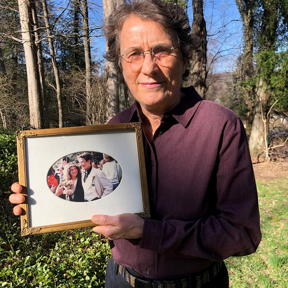 PJ Schimmel standing outdoors holding a photo of his wedding day